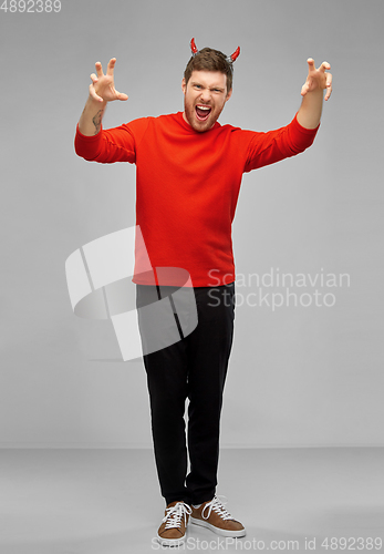 Image of man in halloween costume of devil scaring
