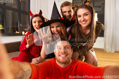 Image of happy friends in halloween costumes taking selfie