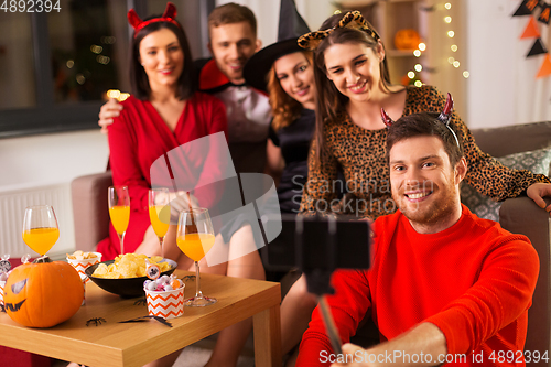 Image of happy friends in halloween costumes taking selfie