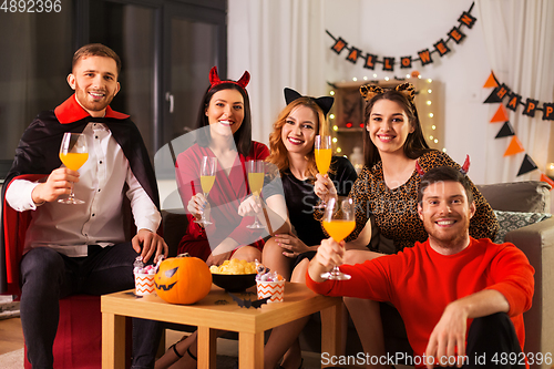 Image of happy friends in halloween costumes at home party