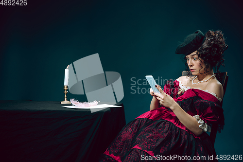 Image of Young woman as Anna Karenina on dark blue background. Retro style, comparison of eras concept.