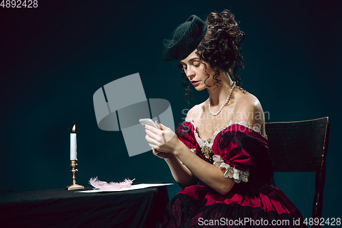 Image of Young woman as Anna Karenina on dark blue background. Retro style, comparison of eras concept.