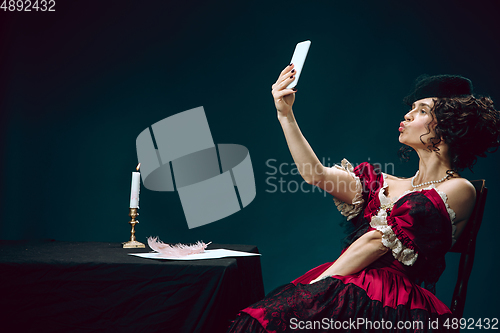 Image of Young woman as Anna Karenina on dark blue background. Retro style, comparison of eras concept.