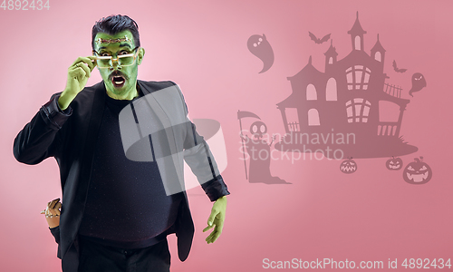 Image of Young man as a zombie on pink background, halloween time, flyer with copyspace
