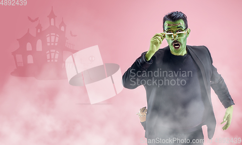 Image of Young man as a zombie on pink background, halloween time, flyer with copyspace