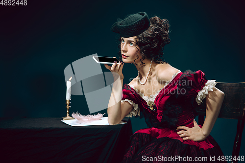 Image of Young woman as Anna Karenina on dark blue background. Retro style, comparison of eras concept.