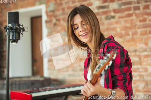 Image of Woman in headphones recording music, singing or making broadcast internet tutorial while sitting in loft workplace or at home