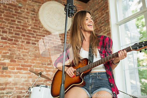 Image of Woman in headphones recording music, singing or making broadcast internet tutorial while sitting in loft workplace or at home