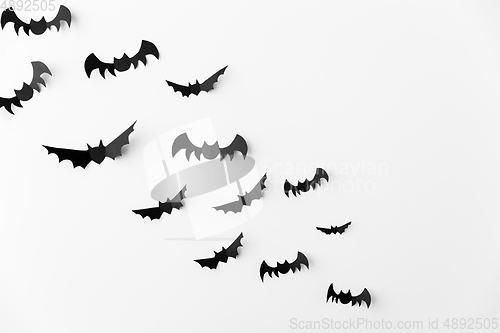 Image of flock of black paper bats over white background