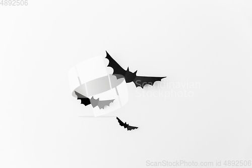 Image of flock of black paper bats over white background