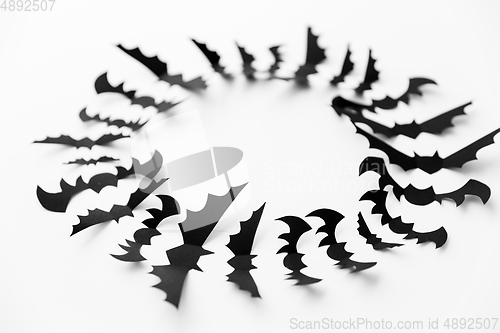 Image of flock of black paper bats over white background