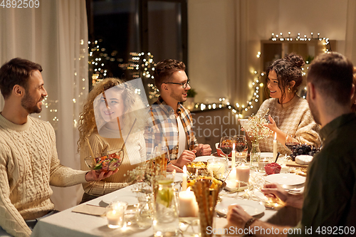 Image of happy friends having christmas dinner at home