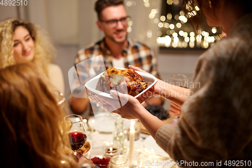 Image of happy friends having christmas dinner at home