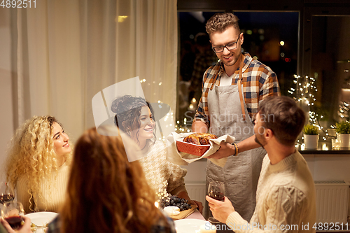 Image of happy friends having christmas dinner at home