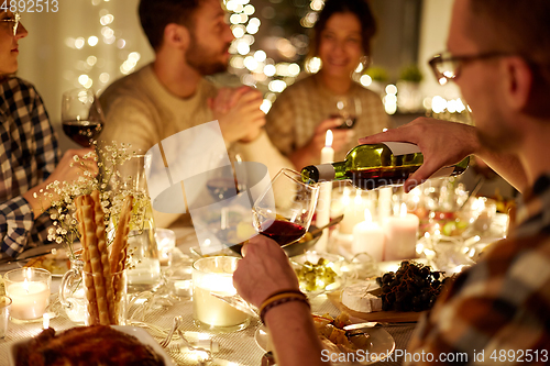 Image of man pouring red wine into glass at christmas party