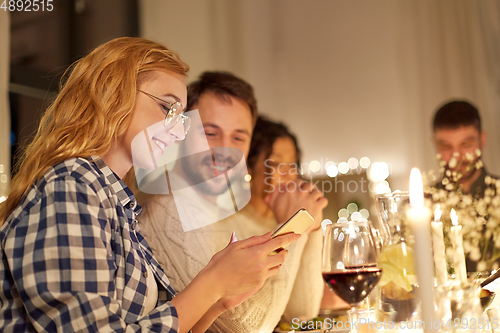 Image of friends with cellphone having dinner party at home