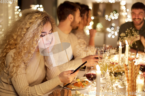 Image of woman with smartphone at dinner party with friends