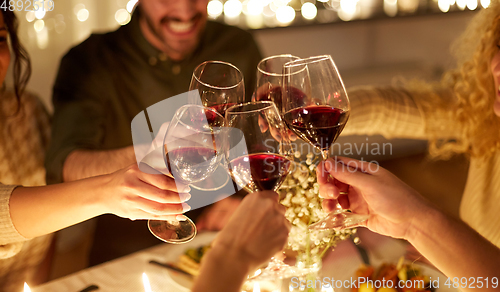 Image of happy friends drinking red wine at christmas party