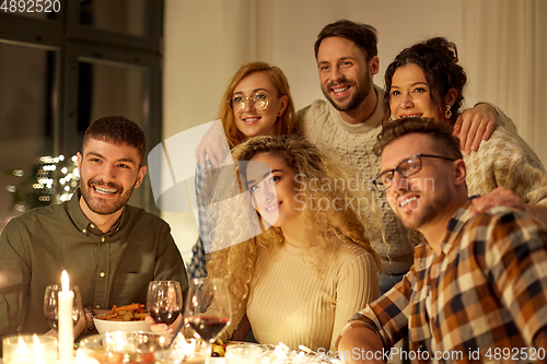 Image of happy smiling friends at christmas dinner party