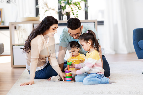 Image of happy family playing with pyramid toy at home