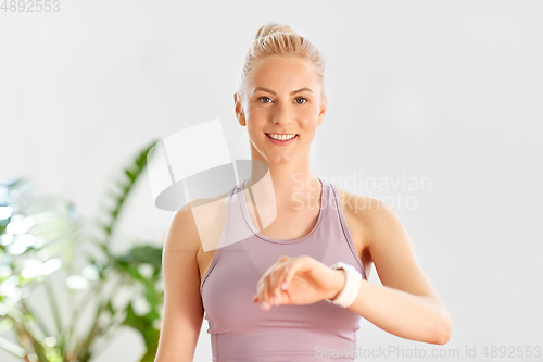 Image of woman with smart watch at home or yoga studio