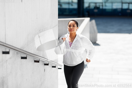 Image of african american woman running upstairs outdoors