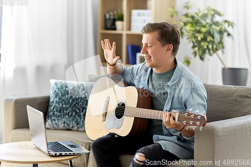 Image of man with laptop and guitar having video call