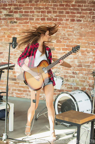 Image of Woman in headphones recording music, singing or making broadcast internet tutorial while sitting in loft workplace or at home