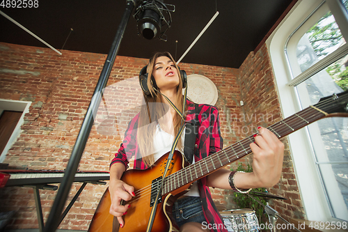 Image of Woman in headphones recording music, singing or making broadcast internet tutorial while sitting in loft workplace or at home