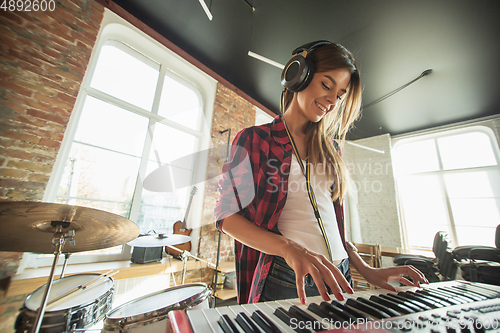 Image of Woman recording music, singing and playing piano while standing in loft workplace or at home