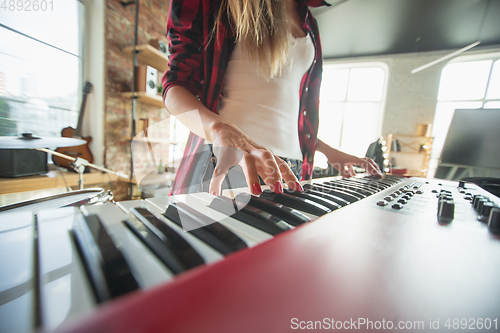 Image of Woman recording music, singing and playing piano while standing in loft workplace or at home