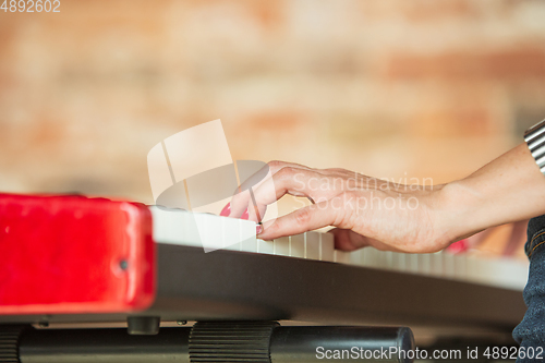 Image of Woman recording music, singing and playing piano while standing in loft workplace or at home