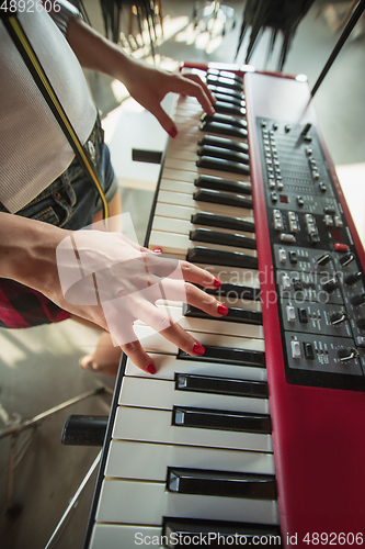 Image of Woman recording music, singing and playing piano while standing in loft workplace or at home