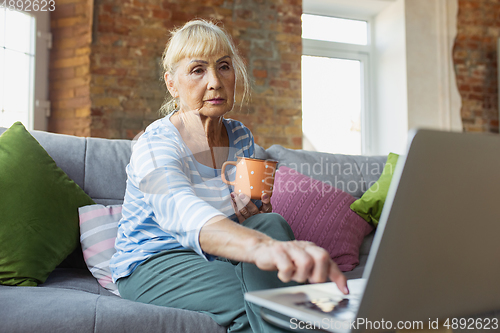 Image of Senior woman studying at home, getting online courses