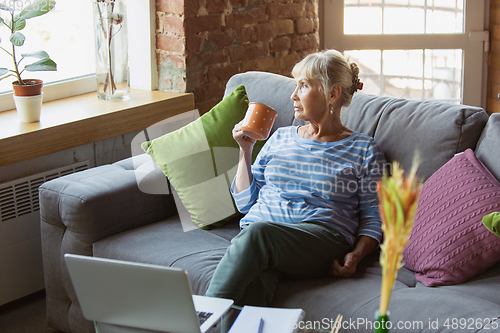 Image of Senior woman studying at home, getting online courses