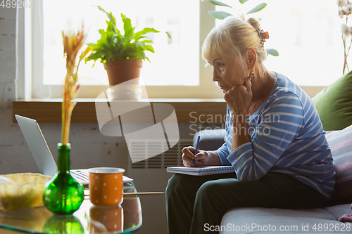 Image of Senior woman studying at home, getting online courses