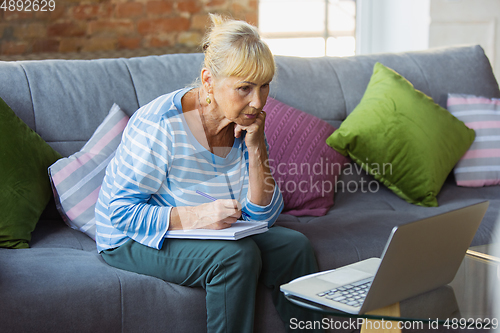 Image of Senior woman studying at home, getting online courses