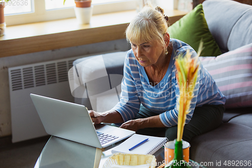 Image of Senior woman studying at home, getting online courses