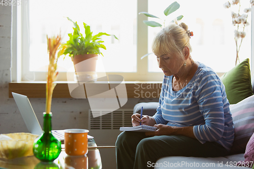 Image of Senior woman studying at home, getting online courses