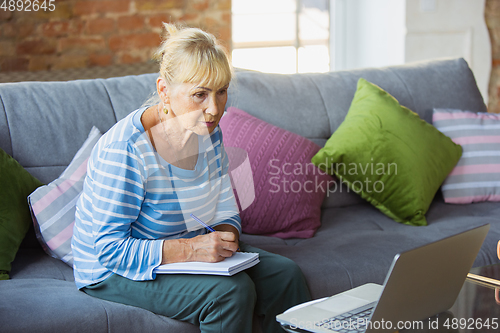 Image of Senior woman studying at home, getting online courses