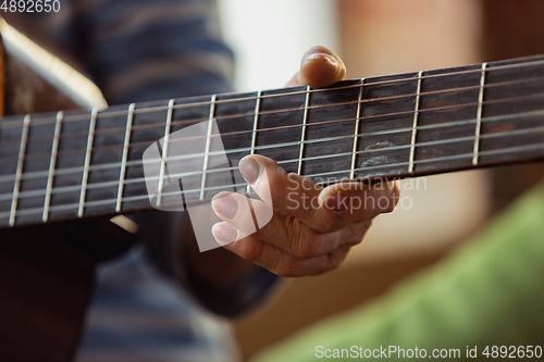 Image of Senior woman playing guitar, close up hands