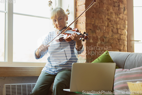 Image of Senior woman studying at home, getting online courses