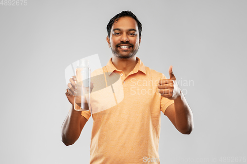 Image of man with water in glass bottle showing thumbs up