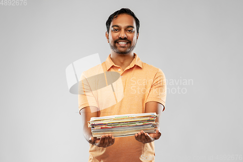 Image of smiling young indian man sorting paper waste