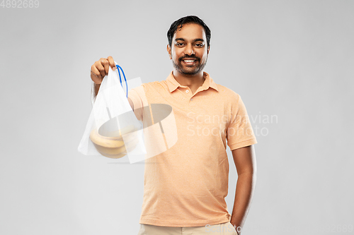 Image of happy man holding reusable string bag with bananas