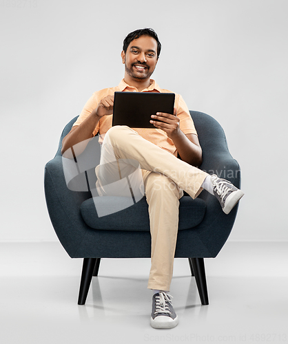 Image of happy indian man with tablet pc computer in chair