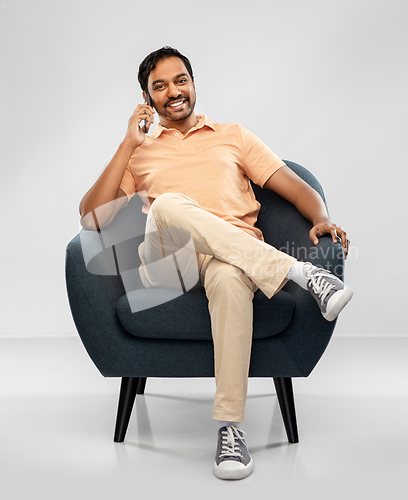 Image of happy indian man calling on smartphone in chair