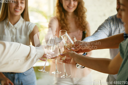 Image of People clinking glasses with wine or champagne. Happy cheerful friends celebrate holidays, meeting. Close up shot of smiling friends, lifestyle