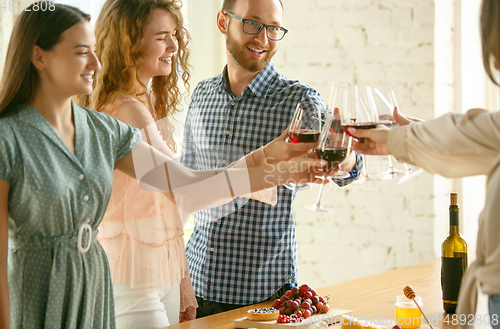 Image of People clinking glasses with wine or champagne. Happy cheerful friends celebrate holidays, meeting. Close up shot of smiling friends, lifestyle