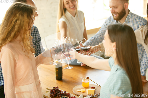 Image of People clinking glasses with wine or champagne. Happy cheerful friends celebrate holidays, meeting. Close up shot of smiling friends, lifestyle